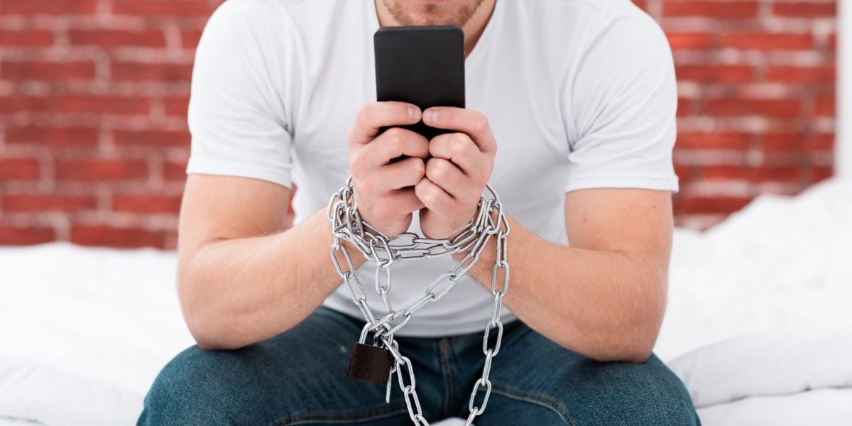 wp-448544ab9c6c521e-man-holding-his-phone-while-he-is-tied-up-with-chains
