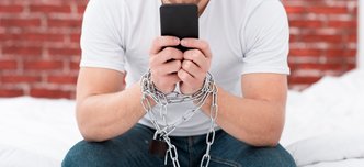 wp-448544ab9c6c521e-man-holding-his-phone-while-he-is-tied-up-with-chains