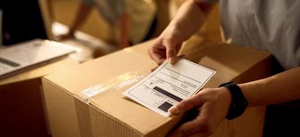 wp-5514e42d8143ff1c-closeup-courier-attaching-address-label-package-while-working-office