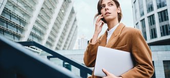 wp-774ed32380b5e435-young-pensive-casual-businesswoman-coat-with-laptop-talking-cellphone-thoughtful