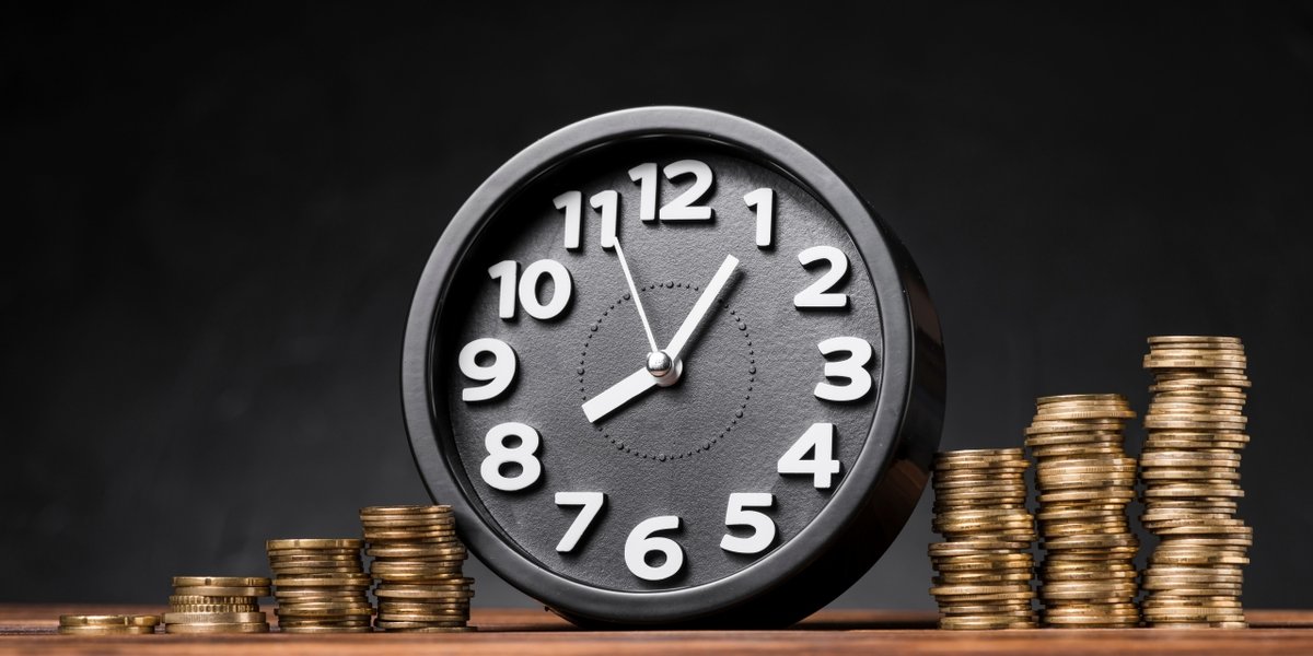 wp-a9bec136c8ae555d-round-clock-increasing-coins-wooden-desk-against-black-backdrop