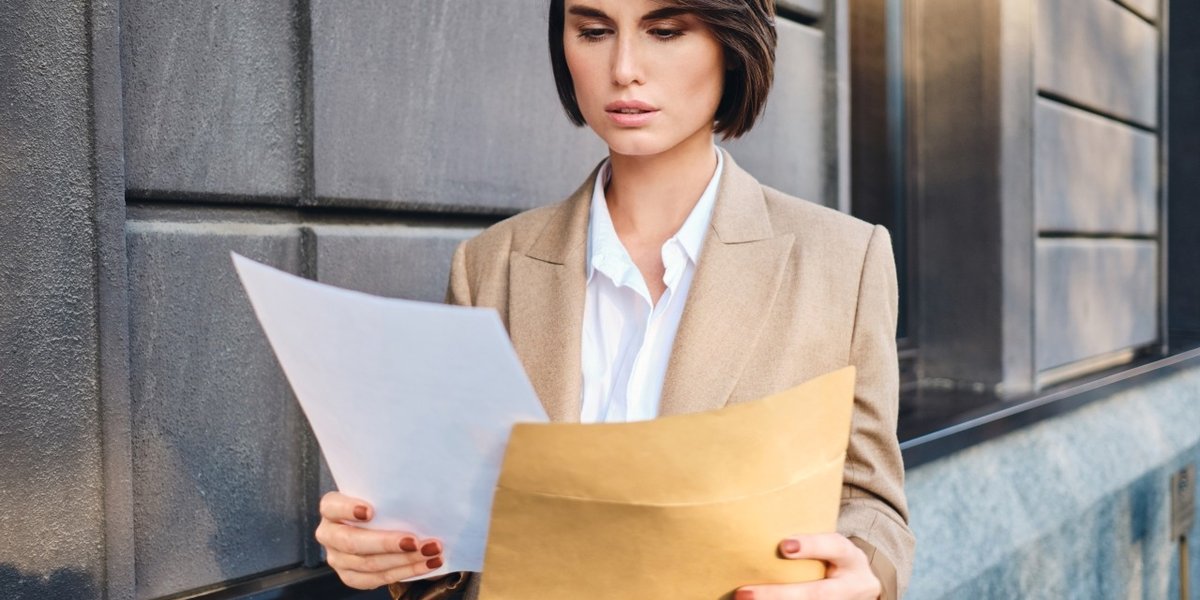 wp-da56187426c76c6b-young-serious-businesswoman-suit-thoughtfully-working-with-papers-city-street
