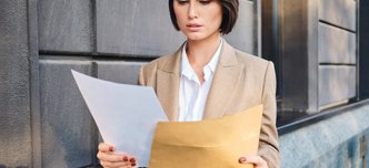 wp-da56187426c76c6b-young-serious-businesswoman-suit-thoughtfully-working-with-papers-city-street